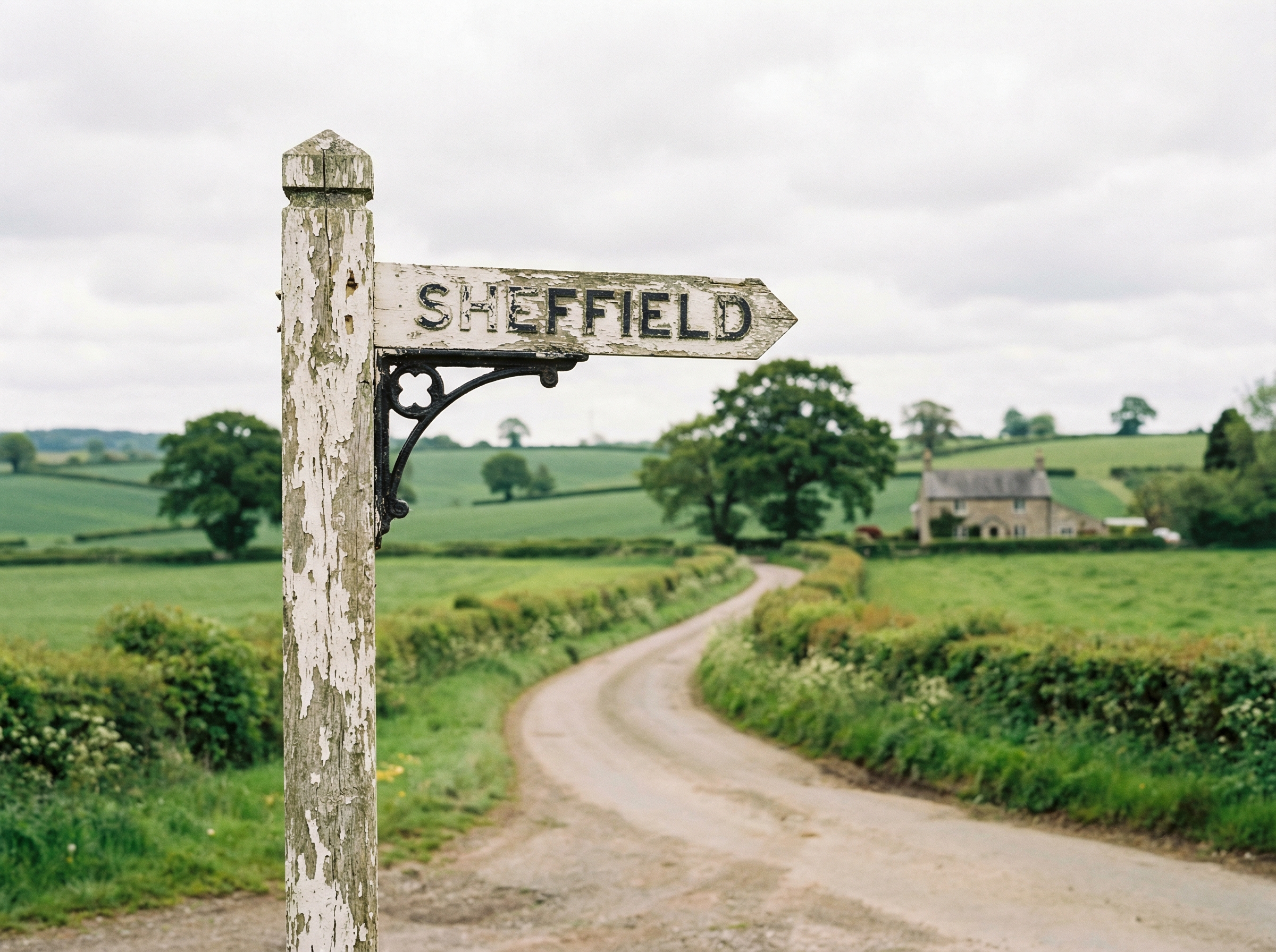 A vintage English countryside road sign post pointing towards Sheffield, lush green fields in the background, soft daylight, cinematic landscape, realistic, 4:3, no text